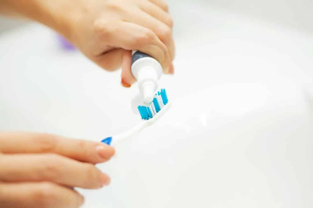 Close up hands woman use toothbrush in light bathroom